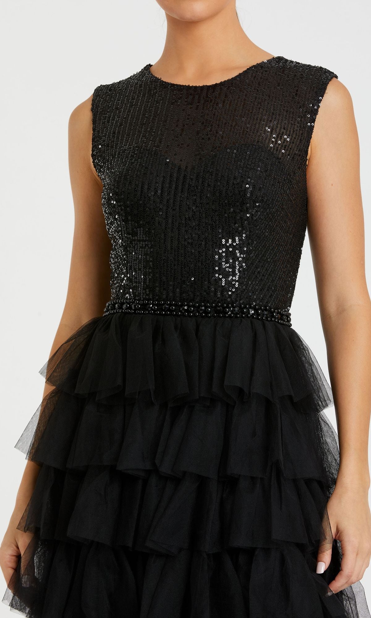 A woman wearing the Mac Duggal 27055, a long black ruffled formal dress with a sequined bodice and layered tulle ruffle skirt.
